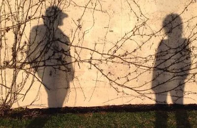 shadow man talks with woman by wall